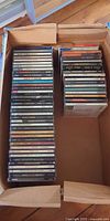 Box containing two stacks of compact discs in jewel cases