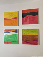 Four square framed abstract paintings mounted on wall