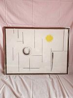 Framed abstract print showing geometric lines, yellow and black circles, numbering and signature visible