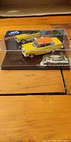 Yellow Mercedes 220SE taxi model in display case with labeled base
