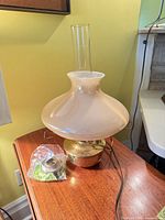 Front view of lamp showing shade, chimney, base, cord, and adapter in bag