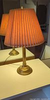 Brass table lamp with pleated shade illuminated