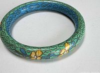 Green cloisonné-style enamel bangle showing floral motif and overall condition