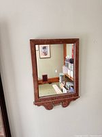 Frontal view of mirror showing frame and carved shelf