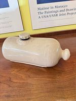 Full view of stoneware hot water bottle showing shape, stopper, and glaze