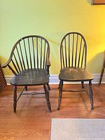 Front view of both Windsor chairs displaying bow backs, spindle arrangement, shaped seats, turned legs