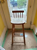 Front view of wooden counter stool showing legs, stretchers, seat and spindle back