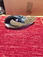 Side view of carved wooden duck decoy showing head, body and painted feather detail