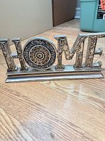 Front view showing HOME wording, ornate detailing and silver finish on black base