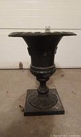 Full view of black cast iron pedestal urn on square base