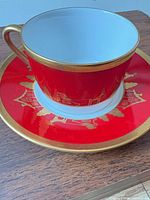Cup on saucer showing red ground, gold rim and handle