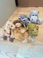 Group shot of five Coca-Cola plush animals on wood floor