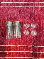 Top view of two highball tumblers and four shot glasses on red rug
