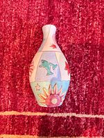 Front view of ceramic bud vase showing fish and sunflower motifs