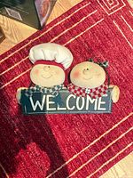 Front view showing two plush gingerbread figures on black WELCOME sign