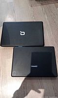 Closed lids of both laptops showing logos and exterior wear