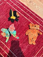 All three plush toys displayed together on red rug