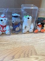 All four Coca-Cola plush toys in acrylic boxes