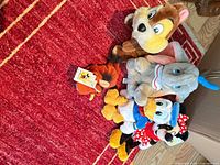 Group shot of all five Disney plush toys on red rug