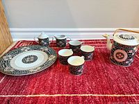 Full tea set displayed on red rug showing all components