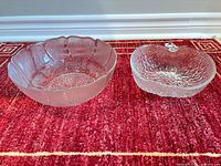 Both clear pressed glass bowls side by side on red rug