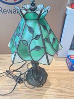 Full view of lamp showing stained glass shade, metal base and cord