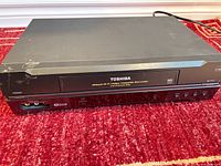 Front view showing model branding, tape slot, control buttons, front A/V inputs