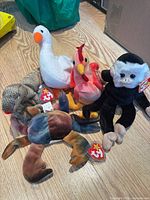 Five Ty Beanie Babies grouped on floor: goose, rooster, monkey, crab, lizard