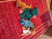 All four plush toys displayed together on red rug