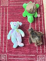 overview of three Ty Beanie Buddies plush toys on red rug