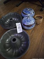 Group shot showing two Bundt pans, two blue ceramic spheres, tan garlic bowl
