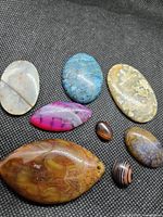 Group shot displaying all eight cabochons on black fabric