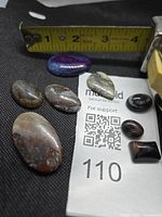 All seven agate cabochons beside tape for scale