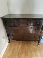 Front view of antique dresser showing drawers, knobs, legs