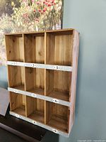 Front view of wooden display shelf showing 9 numbered cubbies