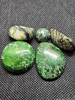 Five jasper cabochons on black fabric, showing colors and patterns