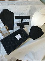 Group of jewelry display items including necklace stands, bracelet bar, ring tray, gold mesh holder
