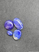Four lapis lazuli cabochons on textured background