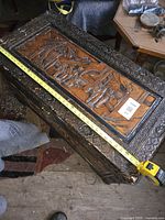 Top view of carved wooden chest with measuring tape showing length around 40 inches