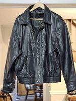 Front view of black Danier leather jacket hanging to show overall style, zipper, pockets and collar
