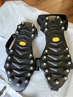 top view of both soles showing metal studs, straps, Vibram logo