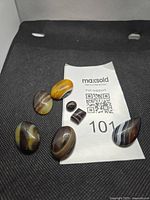 Seven banded onyx cabochons displayed on fabric background