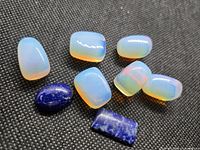 Seven opalite cabochons and two lapis lazuli cabochons on dark fabric