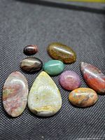All nine agate cabochons grouped on fabric background