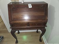 Front view of closed desk showing exterior drawers and carved legs