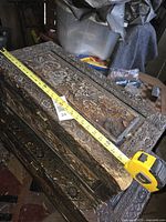 Top view of carved chest with tape measure showing length approx 28 inches