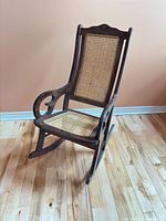 Three-quarter front view of entire rocking chair showing wood frame, cane seat and back, runners