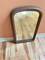 Full view of arched wood mirror leaning against wall