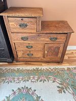 Front view showing stepped form, four drawers, carved door, brass hardware, glass knob