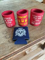 Front view of all four koozies standing upright on table